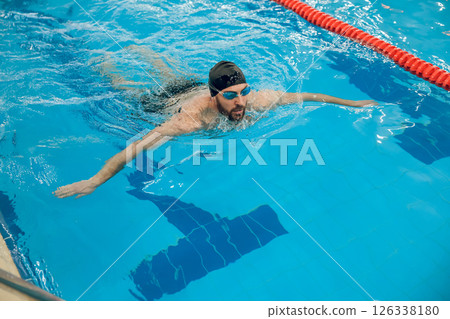 Man in black swimming cap swimming crawl style in the pool 126338180