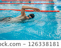 Man in black swimming cap swimming crawl style in the pool 126338181