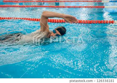 Man in black swimming cap swimming crawl style in the pool 126338181