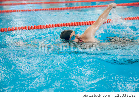 Man in black swimming cap swimming crawl style in the pool Man in black swimming cap swimming crawl style in the pool 126338182