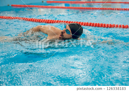 Man in black swimming cap swimming crawl style in the pool Man in black swimming cap swimming crawl style in the pool 126338183