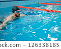 Man in black swimming cap swimming crawl style in the pool 126338185
