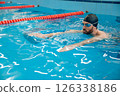Man in black swimming cap swimming crawl style in the pool 126338186