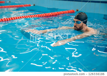 Man in black swimming cap swimming crawl style in the pool 126338186