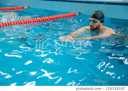 Man in black swimming cap swimming crawl style in the pool 126338187