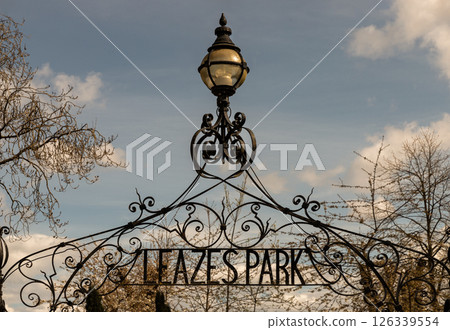 View of Cast iron lamp over the Wrought iron gate is open to the entrance of Leazes park with beautiful sky background. View of Cast iron lamp over the Wrought iron gate is open to the entrance of Leazes park with beautiful sky background. 126339554