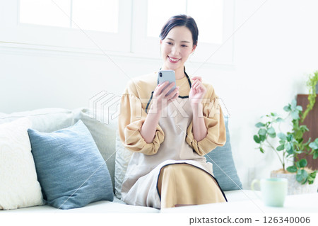 A housewife wearing an apron using a smartphone A housewife wearing an apron using a smartphone 126340006