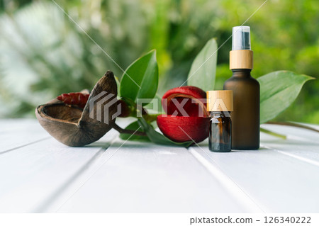 Two brown bottles sit next to a bright flower on a wooden table, highlighting natural cosmetics. 126340222
