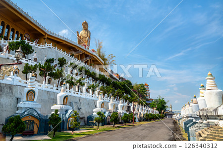 Majestic view of Fo Guang Shan Monastery in Kaohsiung, Taiwan, with the towering golden Buddha statue overlooking a terraced hillside adorned with stupas, bonsai trees, and traditional Chinese Majestic view of Fo Guang Shan Monastery in Kaohsiung, Taiwan, with the towering golden Buddha statue overlooking a terraced hillside adorned with stupas, bonsai trees, and traditional Chinese 126340312
