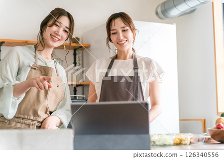 女人在廚房做飯時看著平板電腦 女人在廚房做飯時看著平板電腦 126340556