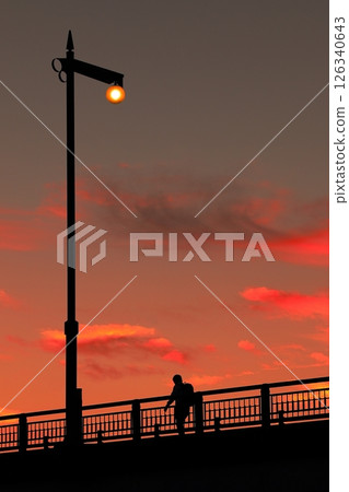 A person standing by a street lamp in the sunset 126340643