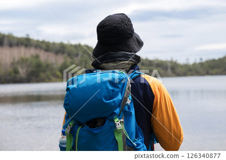 一個人爬山或徒步旅行，沒有臉，看著湖泊和風景 126340877