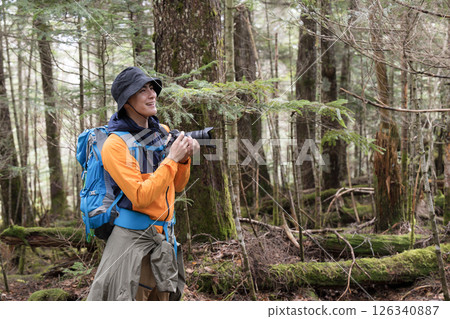 A man observing and photographing plants and creatures in the mountains with fresh greenery. Images of insects, birds, etc. 126340887