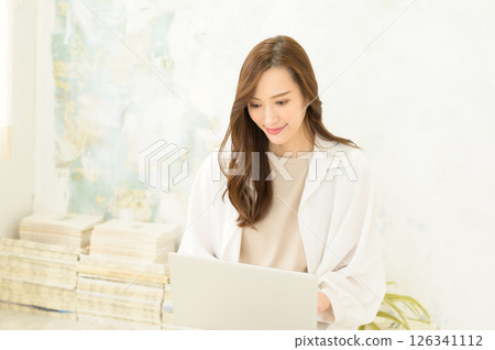 A woman operating a laptop computer on her lap 126341112
