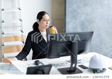 一家建築公司的女員工一邊工作一邊喝咖啡放鬆 一家建築公司的女員工一邊工作一邊喝咖啡放鬆 126341374