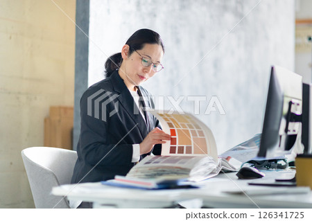 一名建築公司的女員工正在處理排列好的建築材料樣品和文件 一名建築公司的女員工正在處理排列好的建築材料樣品和文件 126341725