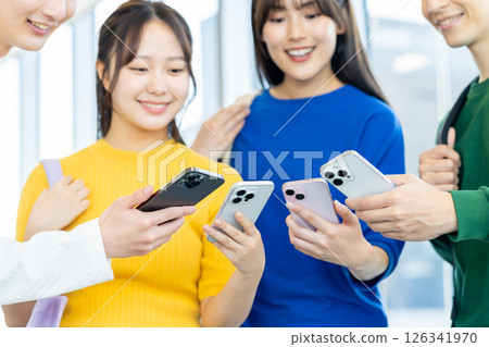 Male and female university students looking at their smartphones. Photo courtesy of Denpa Gakuen, Tokyo Electronics College. 126341970