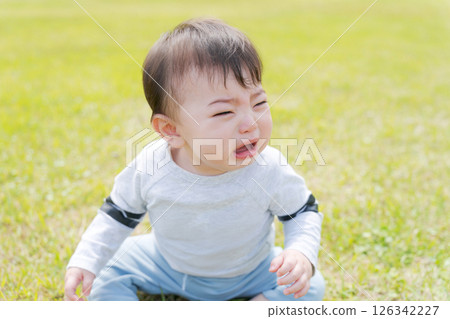 嬰兒坐在草地上哭泣 嬰兒坐在草地上哭泣 126342227