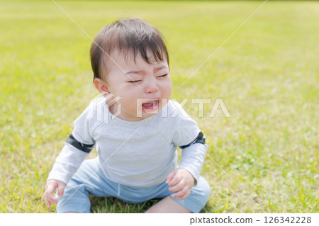 嬰兒坐在草地上哭泣 嬰兒坐在草地上哭泣 126342228