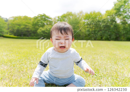 嬰兒坐在草地上哭泣 嬰兒坐在草地上哭泣 126342230