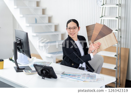 A female employee of a house manufacturer explaining with a sample of flooring 126342319
