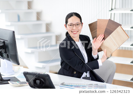 A female employee of a house manufacturer explaining with a sample of flooring 126342323