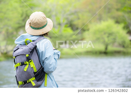 Mountaineer/trekker; woman without face looking at lake and scenery; copy space on the right 126342802