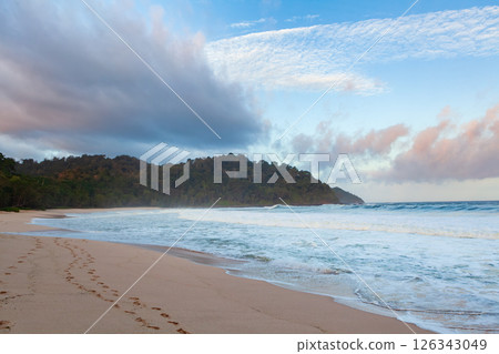 Amazing tropical beach with white sand, blue ocean waves, and lush greenery under a bright sky. Capturing the beauty of an untouched paradise and a perfect vacation escape. 126343049
