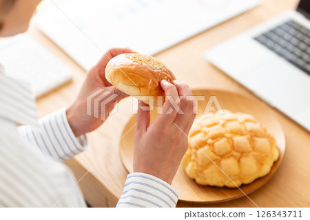 中年婦女在辦公桌上吃麵包 中年婦女在辦公桌上吃麵包 126343711