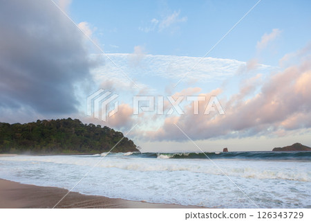 Amazing tropical beach with white sand, blue ocean waves, and lush greenery under a bright sky. Capturing the beauty of an untouched paradise and a perfect vacation escape. Amazing tropical beach with white sand, blue ocean waves, and lush greenery under a bright sky. Capturing the beauty of an untouched paradise and a perfect vacation escape. 126343729