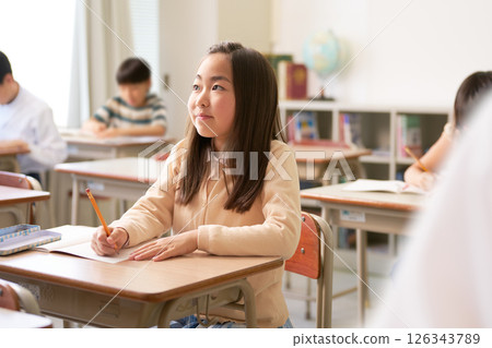 Elementary school girl concentrating in class Elementary school girl concentrating in class 126343789