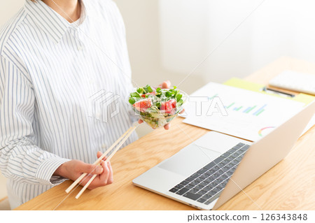 中年婦女在辦公室的辦公桌上吃生蔬菜沙拉 126343848