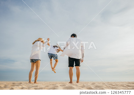 An Asian family bursts with excitement father and mother holding children joyfully jumping into air on beach. beautiful ocean forms picturesque background capturing moment of family happiness. 126345777