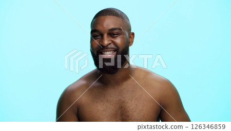 Black man, portrait and smile in studio for skincare, confidence and grooming in morning. African person, dermatology and happy on blue background space for beard care, topless and hygiene in Nigeria 126346859