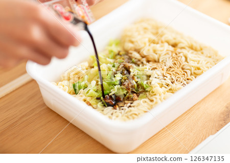 Hands of a middle-aged woman preparing cup noodles Hands of a middle-aged woman preparing cup noodles 126347135
