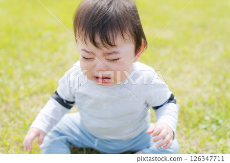 Baby sitting on the grass and crying 126347711