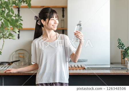 Asian woman hydrating with bottled mineral water after home training 126348506
