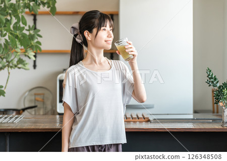 亞洲年輕女性在家客廳訓練後補充水分和營養 126348508