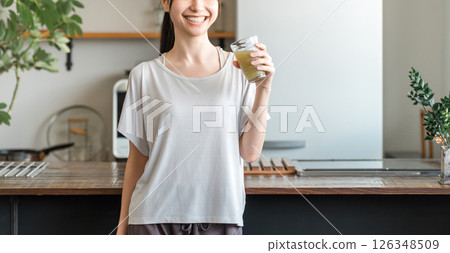 Young Asian woman rehydrating and replenishing nutrients after training in the living room at home Young Asian woman rehydrating and replenishing nutrients after training in the living room at home 126348509