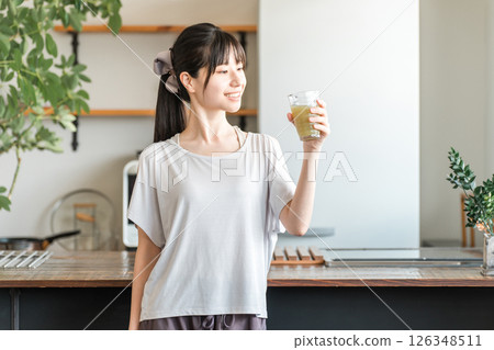 Young Asian woman rehydrating and replenishing nutrients after training in the living room at home 126348511