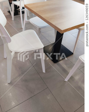 A white chair near the table with a wooden surface. Furniture in the cafe 126349059