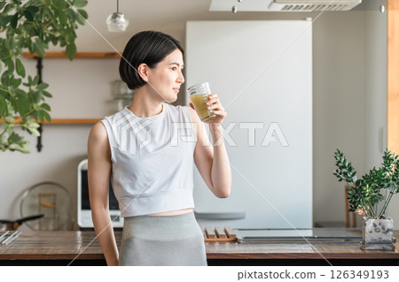 Young Asian woman rehydrating and replenishing nutrients after training in the living room at home 126349193