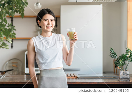 Young Asian woman rehydrating and replenishing nutrients after training in the living room at home 126349195