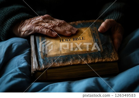Hands lying of an elderly man on large historical bible praying on bible hope faith Christianity. 126349583
