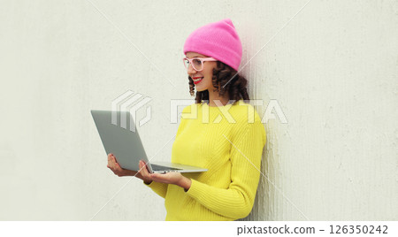 Happy modern young woman working on laptop, freelancer girl looking at computer in colorful clothes 126350242