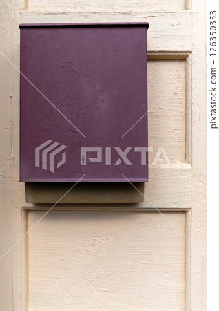 A purple mailbox mounted on a wooden door in a quaint residential area during the daytime A purple mailbox mounted on a wooden door in a quaint residential area during the daytime 126350353