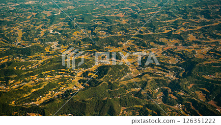 View From Airplane Window On Private Buildings, China. Mountainous Wooded Terrain Landscape Of China. Porthole View Or Called Bull's-eye Window 126351222