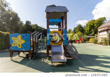 Colorful playground structure with slide and climbing features in a sunny park setting Colorful playground structure with slide and climbing features in a sunny park setting 126351364