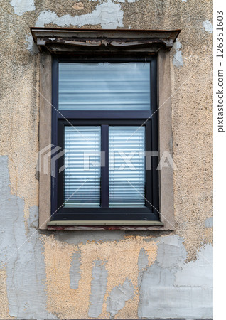 Close-up view of a vintage window against a peeling wall in a quaint building exterior 126351603
