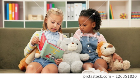 Girls, reading or sofa with book for story time, education or learning together at elementary school. Children, kids or students with novel on couch for childhood development, fiction or imagination 126351820